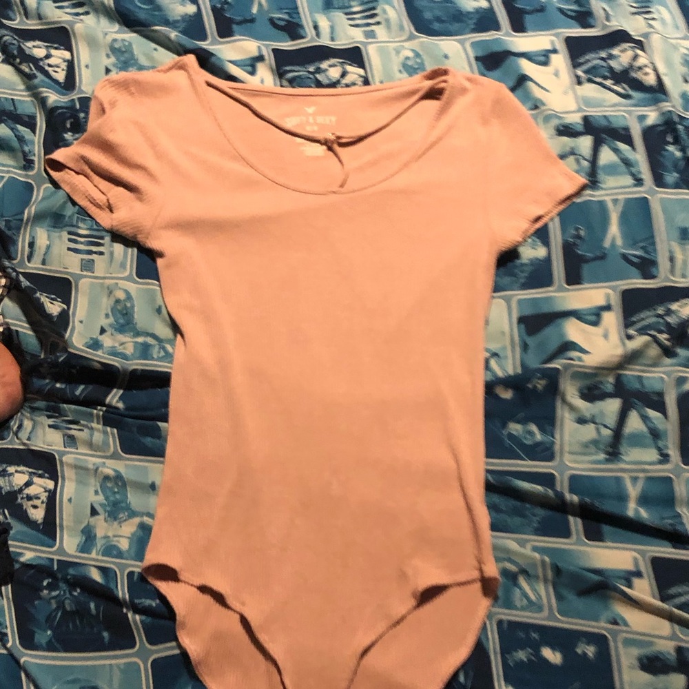 Pink blush body suit. Strap details on chest with gold detail. Snap closure